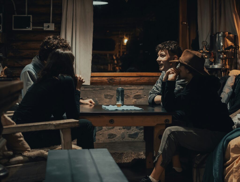 Group of friends sitting down at a table, talking among themselves