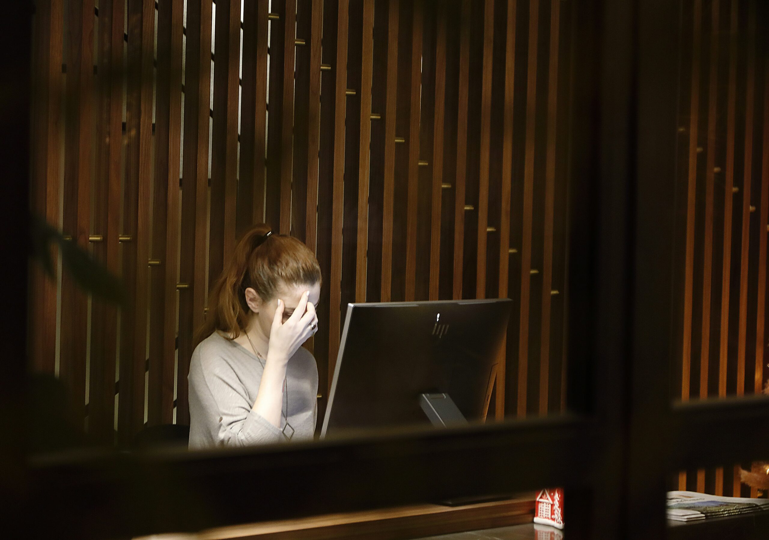 Young woman in a darkened room with a strained expression in front of a computer