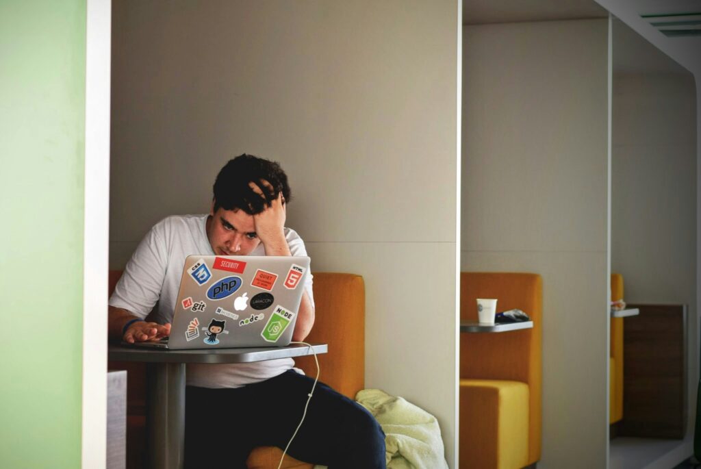 Young man in work booth with a strained look on his face